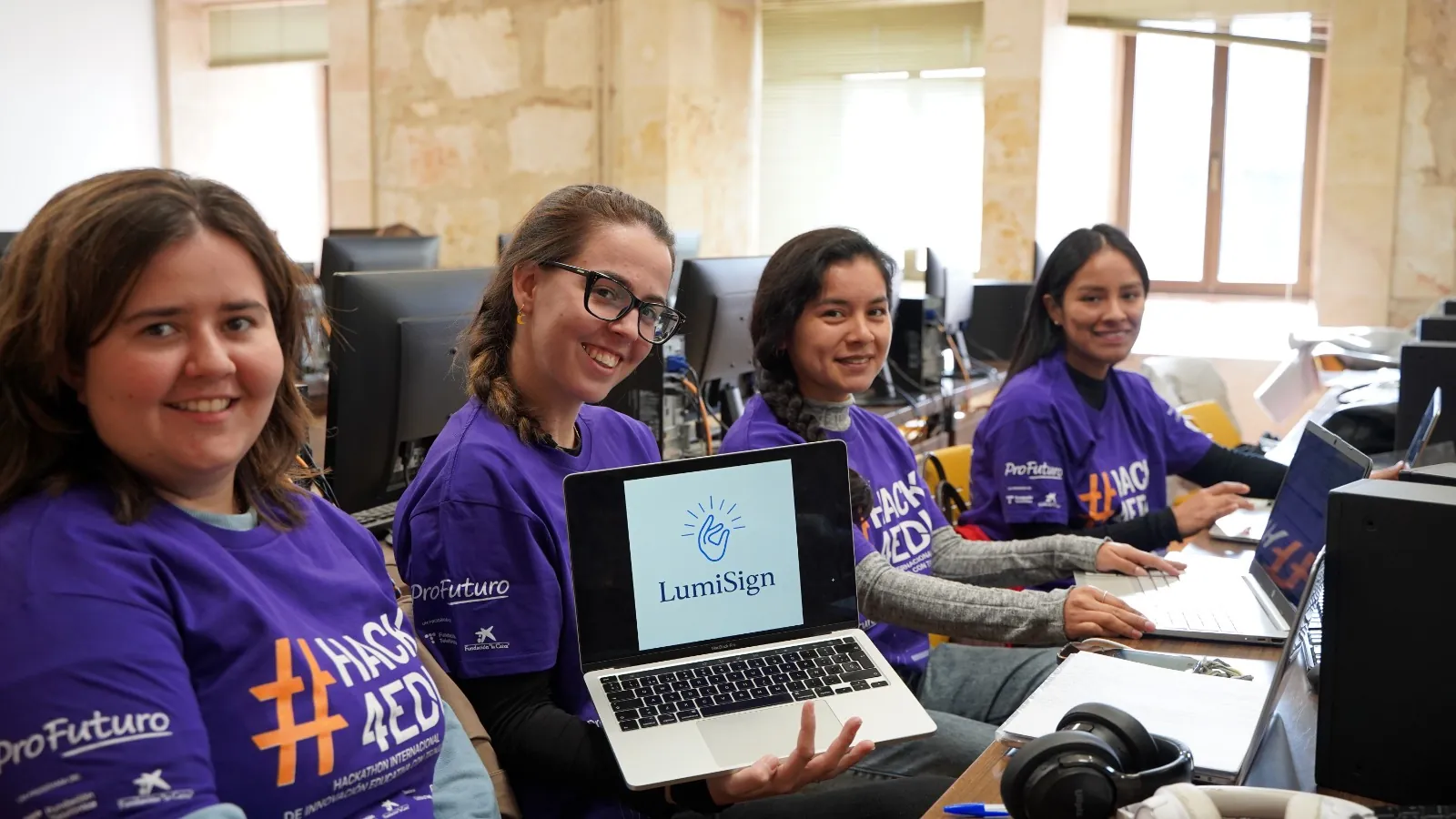 Integrantes del equipo LumiSign mostrando su proyecto en una computadora